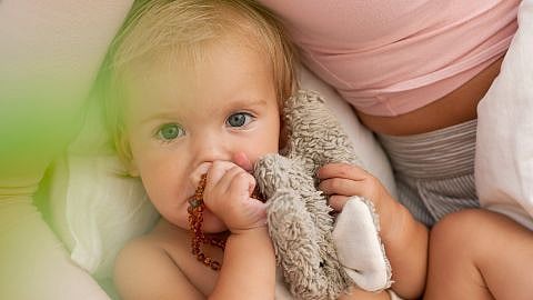 Baby holding a teething necklace and bunny