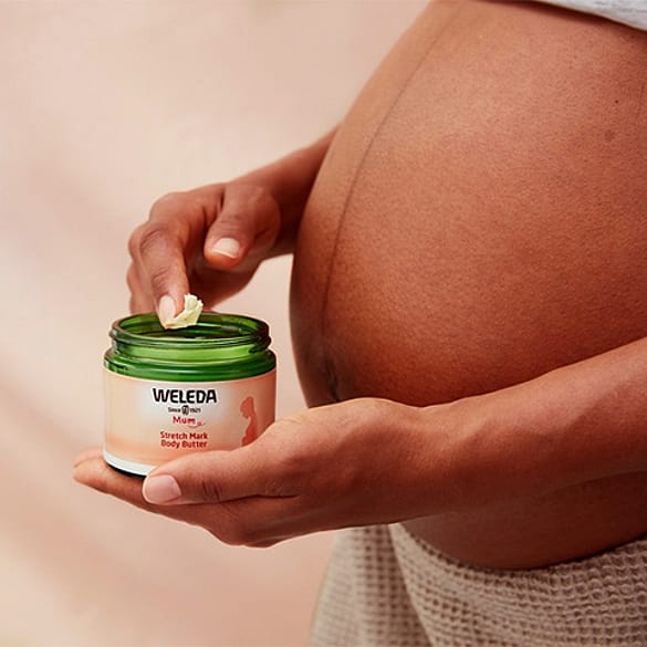 Pregnant person holding Stretch Mark Body Butter on their hand