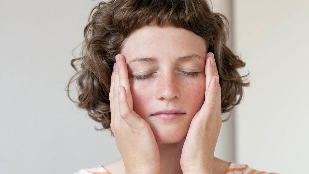 woman is gently applying cream to her face