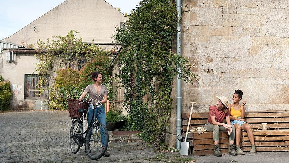 girls resting on a bench, girl pushing bike
