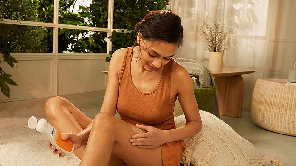 woman gently applying weleda product on her leg.