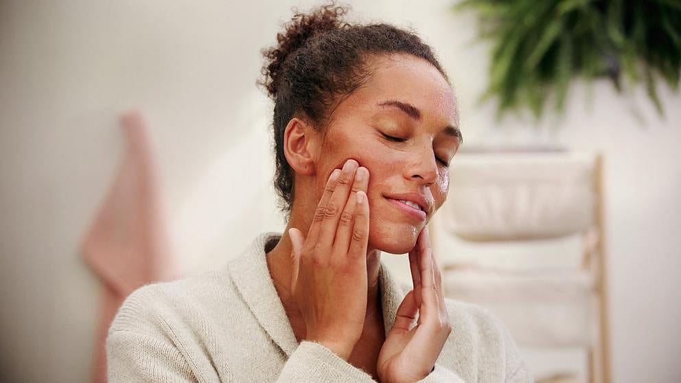 Woman putting a nourishing mask on her face.