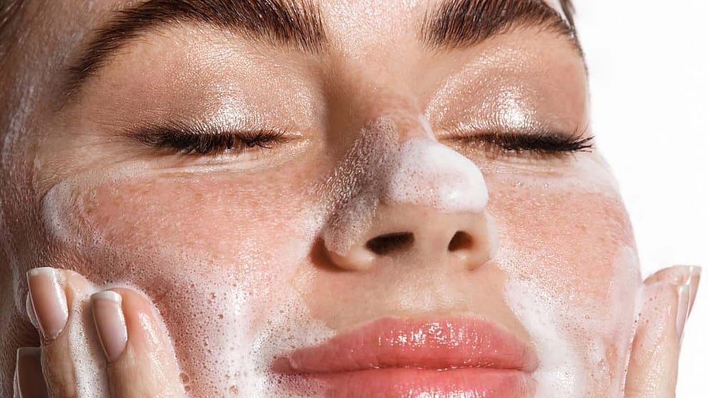 Woman cleansing her face with closed eyes