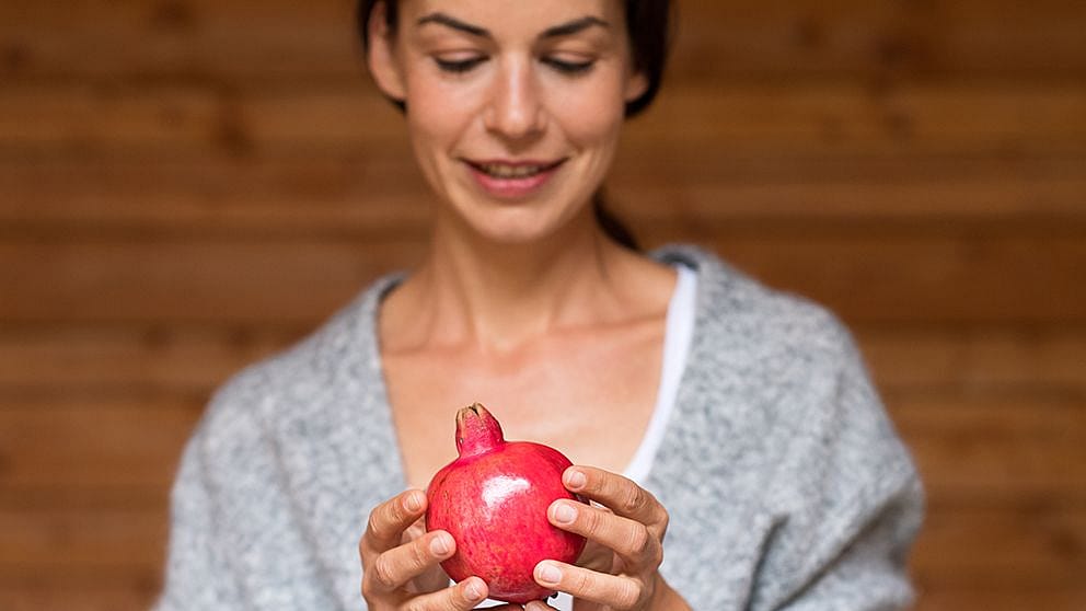 Woman holding pomegranate fruit.