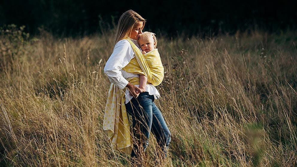 Woman in a field carrying baby.