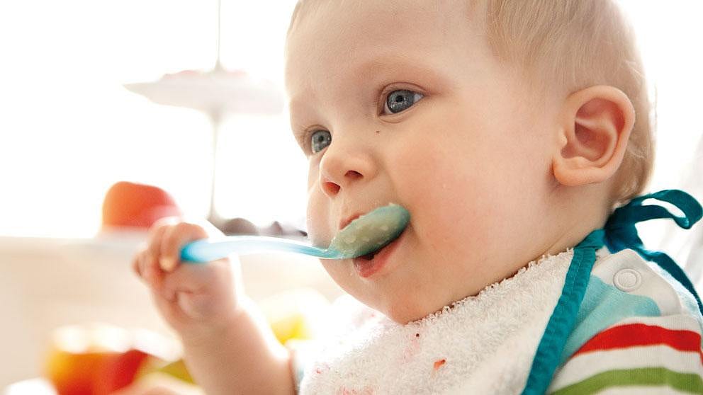 Baby holding a food to their mouth.