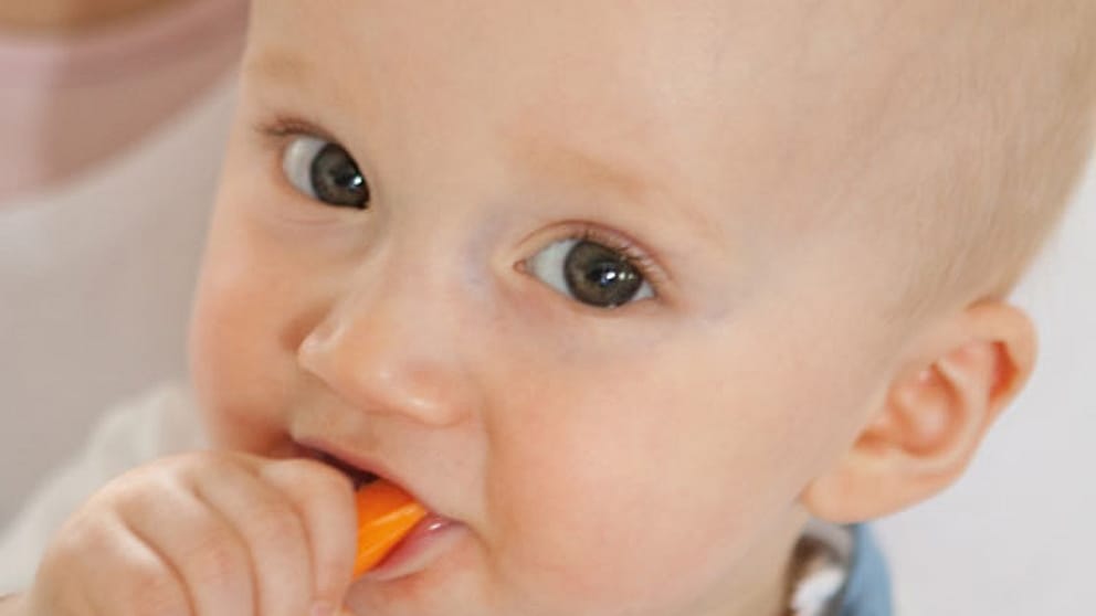Baby eating foods and looking up.