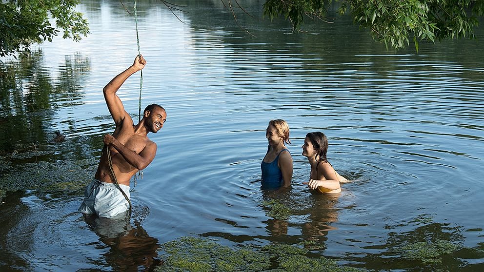 Two women and a man playing in a lake.