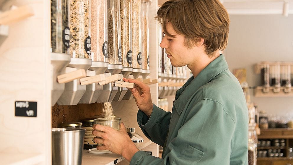 Man dispensing bulk foods into a jar.