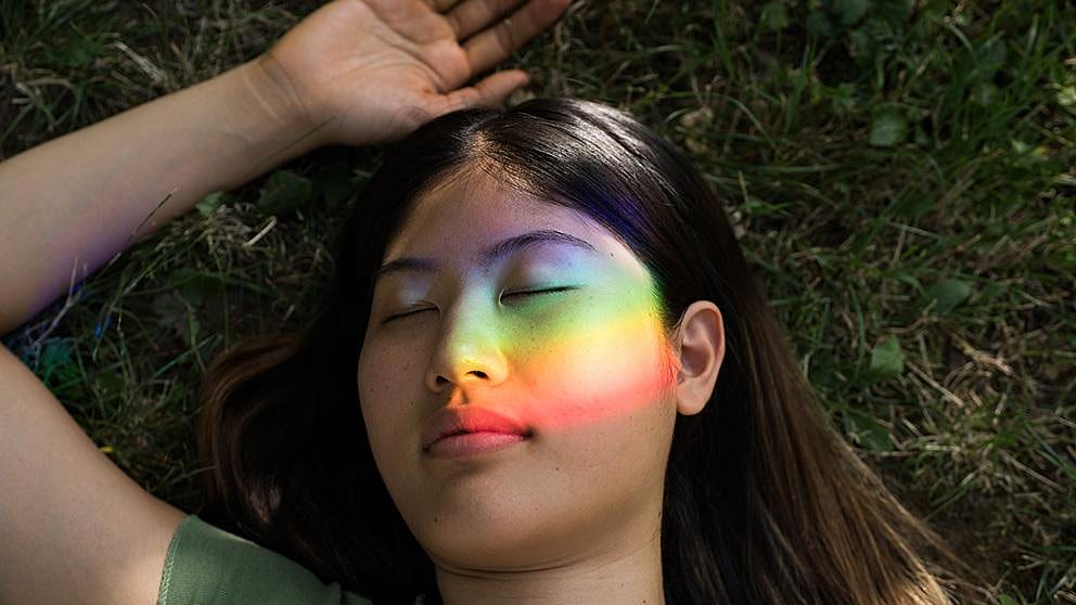 Girl with rainbow light reflected on her face.