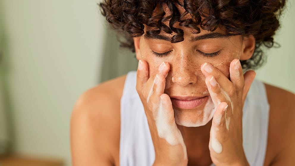 Woman washing her face with foaming face wash cleanser.