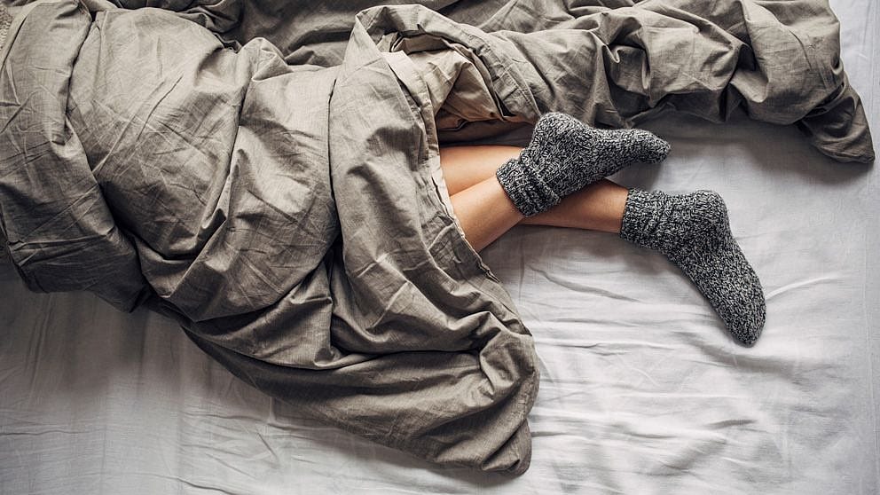 Person uneer a blanket and feet with socks showing.