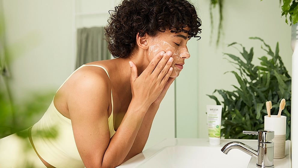Girl in bathroom washing her face with Blemished Skin Purifying Gel Cleanser