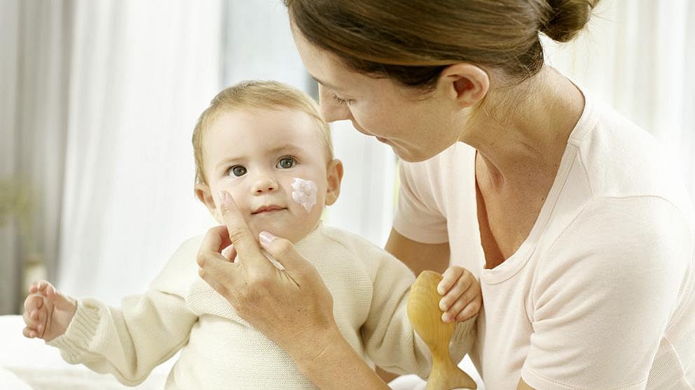 Mother applying calendula face cream to baby