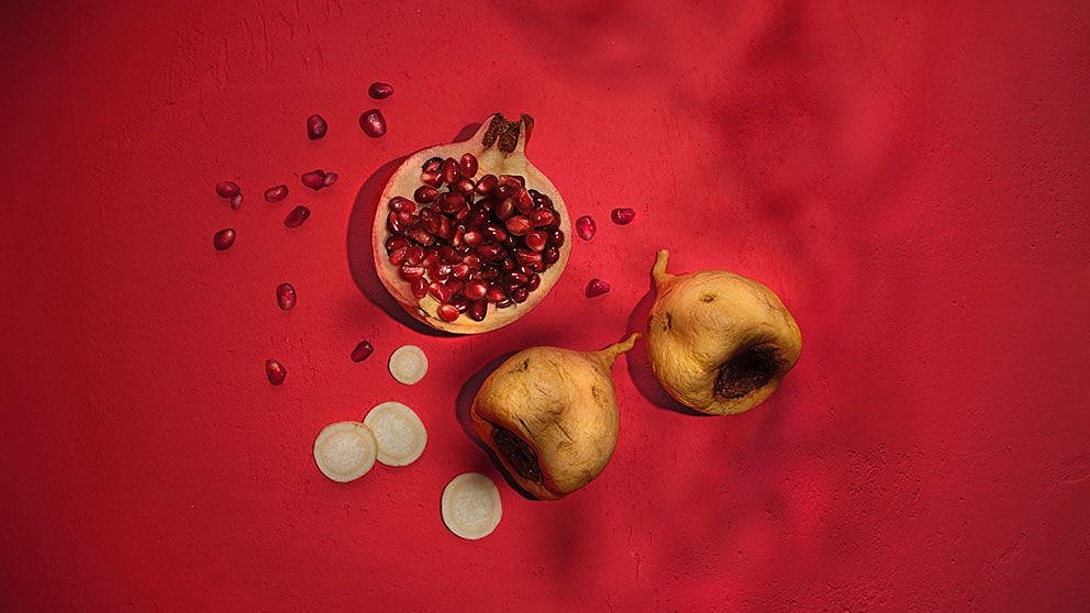 Pomegranate fruit cut in half with seeds and maca fruit sliced